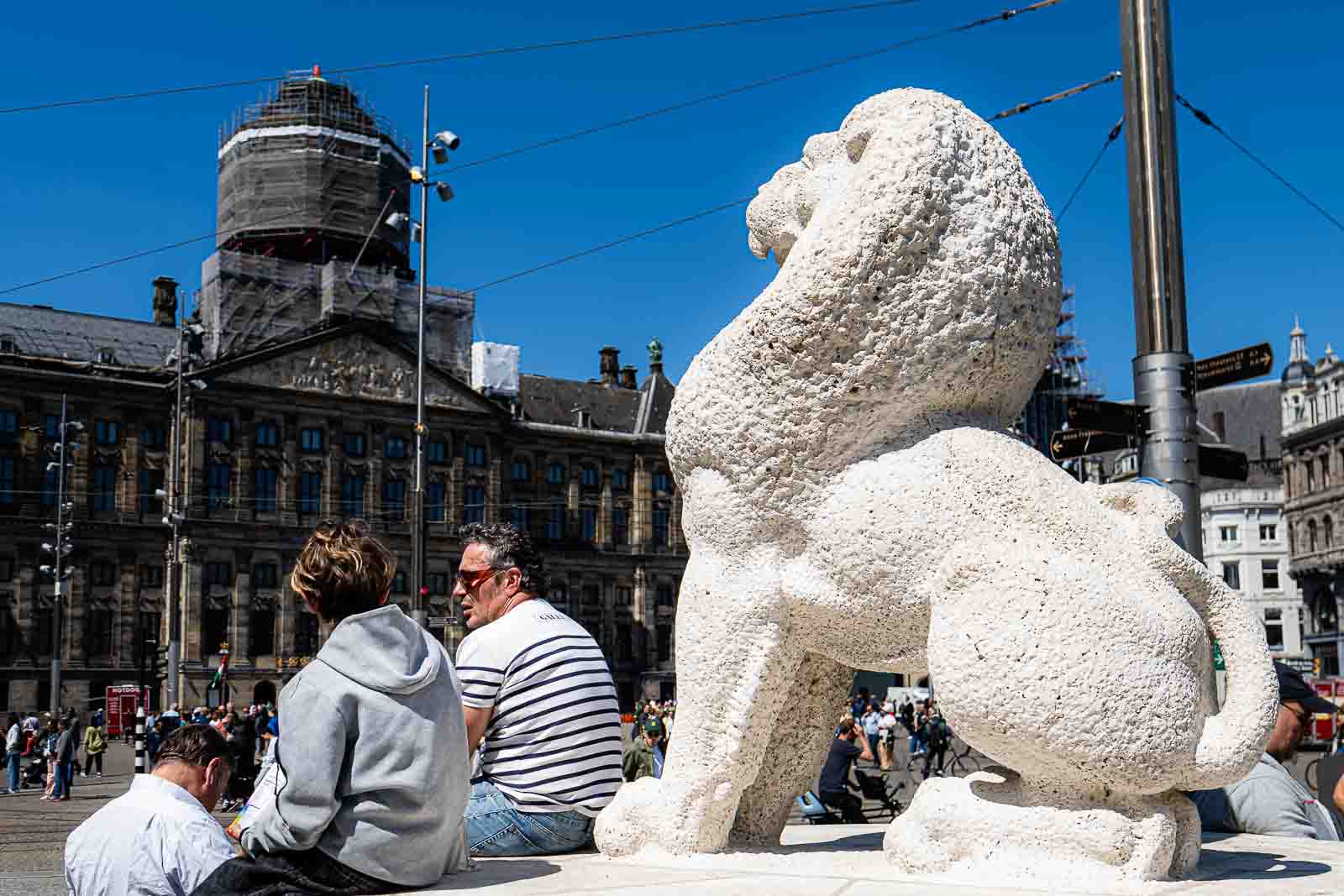Tourists resting at lion statue Dam Amsterdam